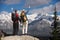 Couple raising their hands on the top of mountains in front of snow-covered mountains