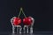 Couple of red cherries placed on beautiful silver chairs on black background