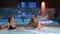 Couple relaxes in an outdoor hot tub. Happy young woman and man relaxing in hot water near the pool.