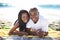 Couple, relaxing on beach towel and portrait with love, sand and romantic for summer vacation. African, resting and