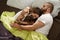 Couple relaxing on the bed with their playful bulldog puppy while embracing