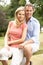 Couple Relaxing In Countryside Sitting On Fence