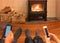 Couple relaxing by fire looking at separate mobile devices