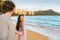 Couple relaxing holding hands having fun on Waikiki beach Hawaii vacation. Happy tourists people in love walking at