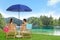 Couple relaxing on sun loungers near river and mountains. Luxury vacation
