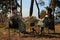 Couple resting in camping chairs and enjoying hot drink near bonfire outdoors