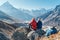 Couple resting on the Everest Base Camp trekking route near Dughla 4620m. Backpackers left Backpacks and trekking poles and