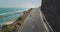 Couple rides on a road between mountain and ocean