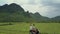 Couple rides scooter along bumpy road in fields upper view