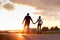 Couple riding on roller skates, holding hands on the street during sunset