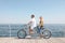 Couple riding tandem bike near sea