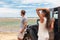 Couple on a road trip travel holiday in Hawaii driving car on beach. Young people tourists enjoying vacation