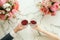 Couple on romantic date. Friends clinking glasses, top view. Red wine, flowers around on marble table. Wedding celebration, party