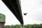 Couple on rope under bridge flying over river water on sky background