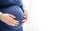 Couple`s hands hold pregnant woman`s belly bump