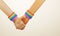 Couple`s hands holding hands with rainbow necklace, symbol LGBT