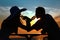 Couple\'s silhouettes on sunset drink from glasses