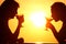 Couple\'s silhouettes on sunset drink from glasses