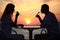 Couple\'s silhouettes on sunset drink from glasses