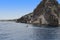 A couple is sailing on a yacht along a rocky shore.