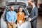 Couple with sales manager near the car in the showroom
