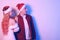 Couple in santa hats, new year, christmas. Lovers in neon light. Surprised couple looking to the side at empty space for text