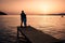 couple seated on a wooden jetty, looking a colorful sunset on the sea , men and woman watching sunset in Crete Greece