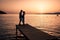 couple seated on a wooden jetty, looking a colorful sunset on the sea , men and woman watching sunset in Crete Greece