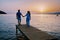 couple seated on a wooden jetty, looking a colorful sunset on the sea , men and woman watching sunset in Crete Greece