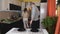 The couple served together table for family dinner. The couple arranges Cutlery and cooked meals on the table.