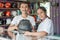 Couple of shop assistants holding a helmet against a helmet display rack background