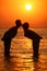 Couple silhouette kisses in sea on sunset