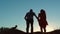 Couple silhouette running toward the sun outdoors at sunset dramatic sky background. young happy couple jumping on