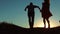 Couple silhouette running toward the sun outdoors at sunset dramatic sky background. young happy couple jumping on