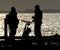 Couple in silhouette talking on seaside pier.