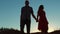 Couple silhouette walking. slow motion video. holding hand toward the sun outdoors at sunset dramatic sky background and