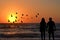 Couple silhouettes holding hands looking at sunrise on the beach