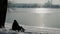 Couple sit on bench admiring reflection of sun rays in river in winter.