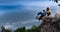 Couple sit down cliff looking view