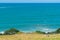 Couple sit in grass on wide slope looking at ocean view