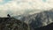 Couple sits on bench at top of mountain, the Caucasus. Bench stands on edge of mountain overlooking huge Caucasus