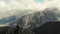 Couple sits on bench at top of mountain, the Caucasus. Bench stands on edge of mountain overlooking huge Caucasus