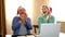 A couple sits at a table wearing Christmas hats, and a gift box arrives for them