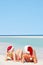 Couple Sitting On Beach Wearing Santa Hats