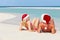 Couple Sitting On Beach Wearing Santa Hats