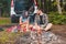 couple sitting on blanket near bonfire white suv vehicle on background