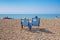 Couple sitting in deckchairs on a beach.