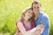 Couple sitting outdoors holding flower smiling