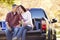 Couple Sitting In Pick Up Truck On Camping Holiday