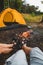 couple sitting resting near camping fire yellow tent on background